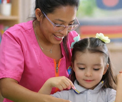 Maestra enseñando a niña pequeña de Mi liceo taller materno